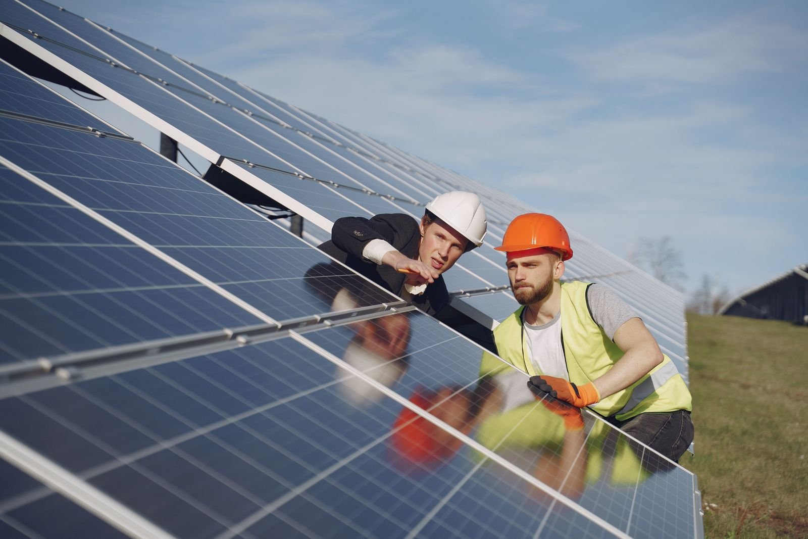 Zwei Monteure mit Helm prüfen gemeinsam eine Solaranlage