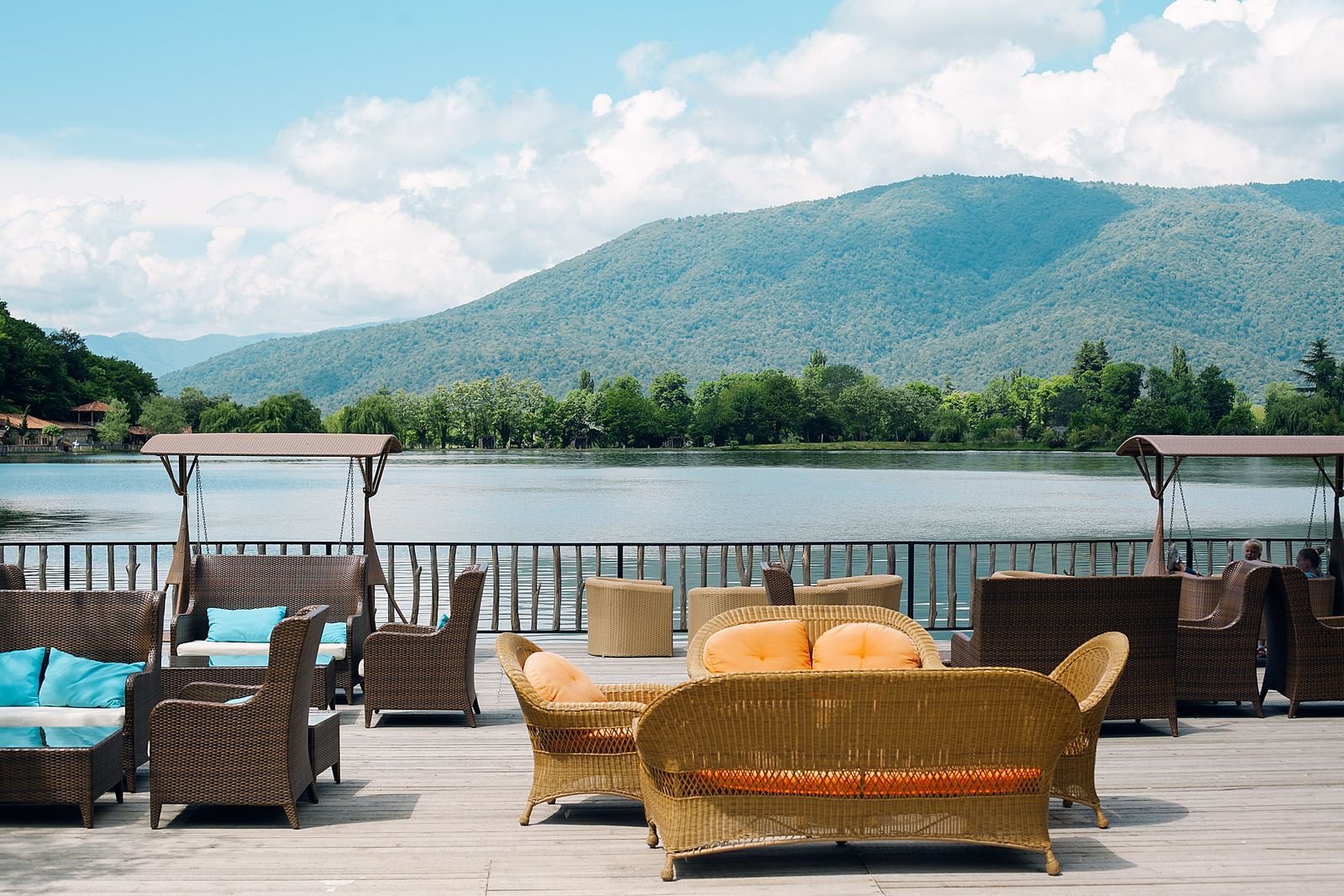 Sonnige Terrasse mit Korbmöbeln und Blick auf See und Berge
