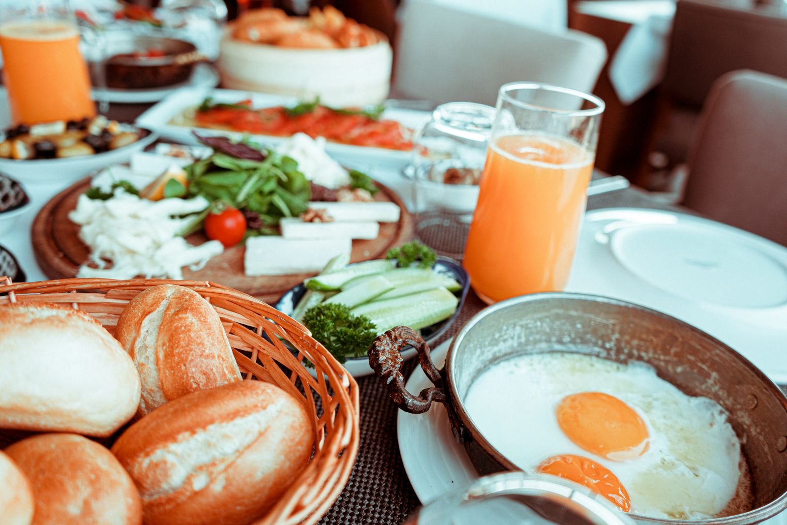 Frühstückstisch mit Semmeln, Spiegelei, Käse und Orangensaft