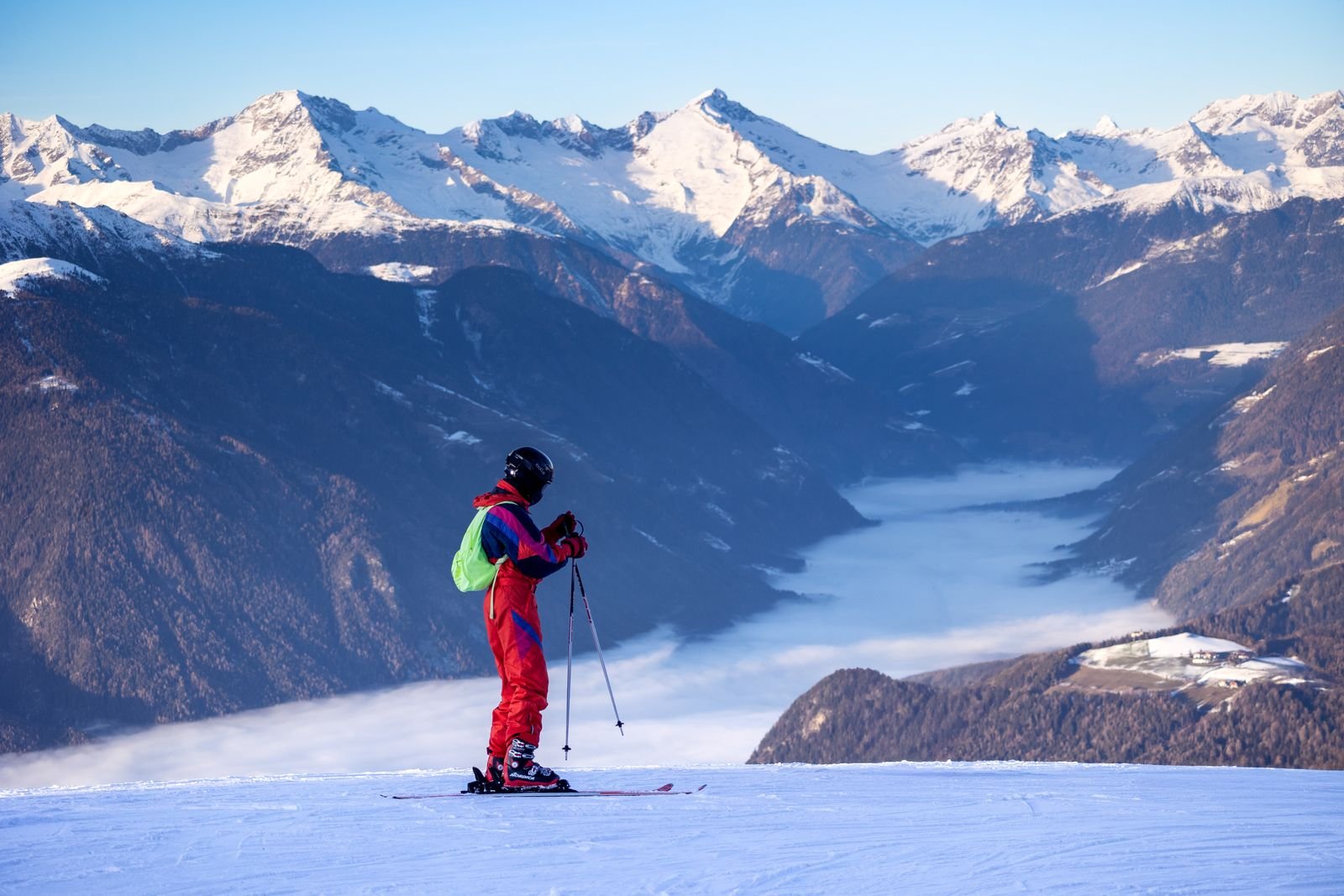 Skifahrer auf der Piste vor verschneiten Alpengipfeln