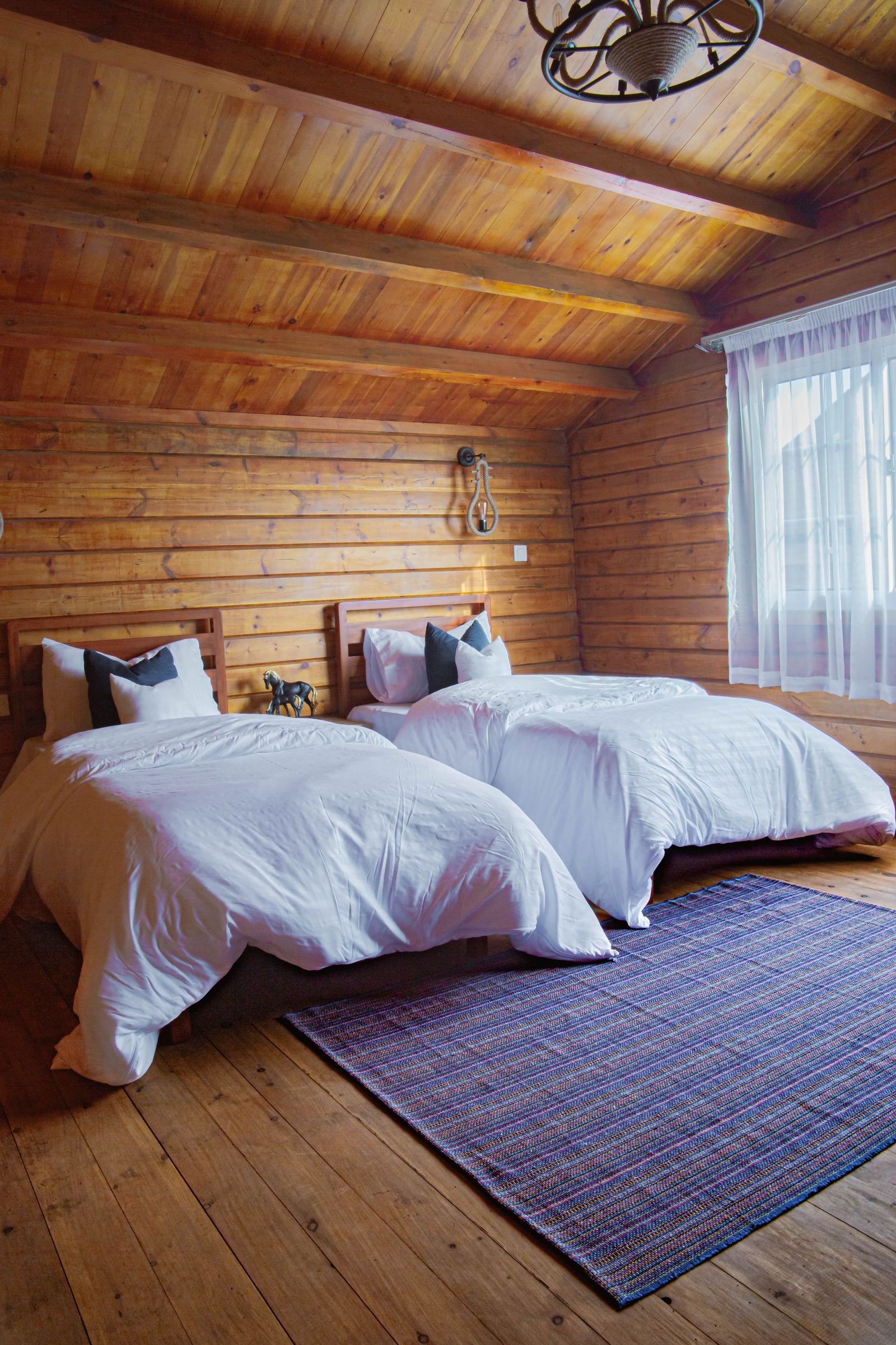 Gemütliches Zimmer mit Holzwänden, Holzdecke und weißer Bettwäsche