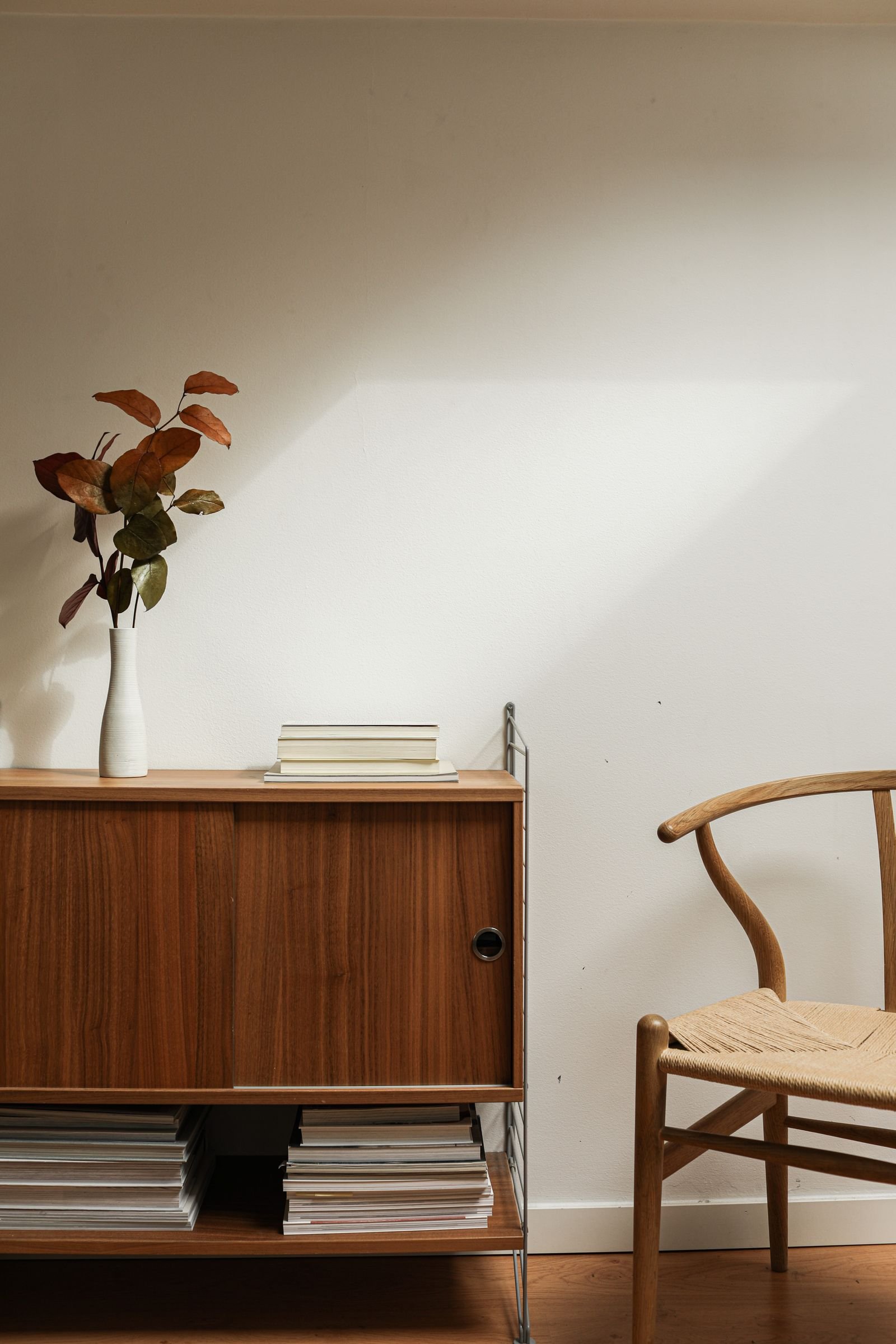 Holz-Sideboard und Holzstuhl in hellem Wohnraum
